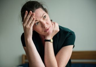 A military veteran woman with her hand on her forehead, reflecting deep thought and the need for mental health care.