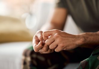 Close-up of a veteran’s clenched hands, representing emotional tension and the process of seeking help.