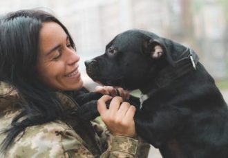 A female veteran in uniform smiling and bonding with her service dog, symbolizing the therapeutic connection between veterans and their emotional support animals at Solara Mental Health.